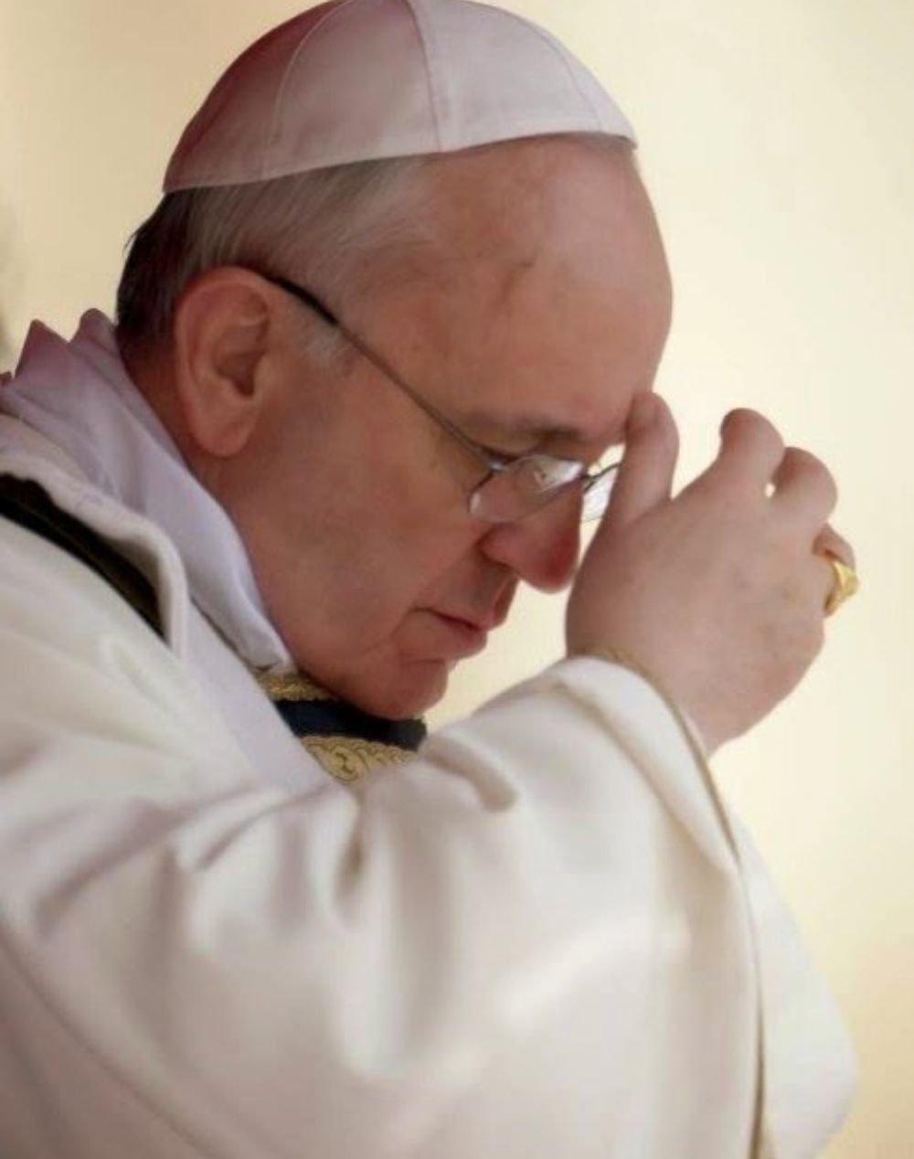 Papa Francisco de cabeça baixa, com as mãos unidas em oração