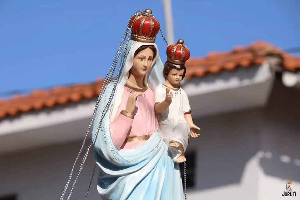 Estátua de Nossa Senhora da Saúde coroada, com o Menino Jesus, sobre um telhado