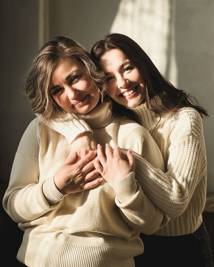 Duas mulheres abraçadas, uma entregando um presente à outra